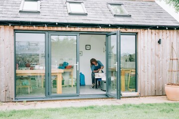 woman spinning clay on a pottery wheel in her home studio in the yard