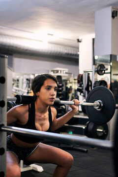 Young woman lifts weights in a gym