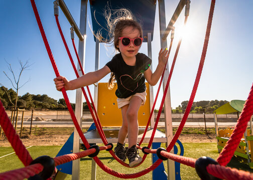 Young girl on climbing frame at outdoor park in sunshine