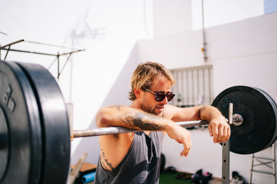 Blond athlete man resting on barbell