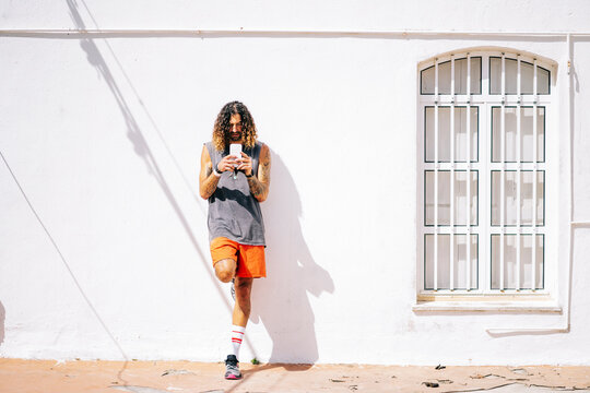 Long haired athlete man using mobile phone in outdoor patio
