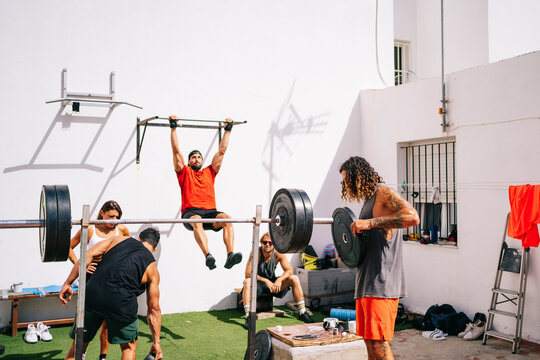 A group of sporty friends perform different exercise routines outdoors