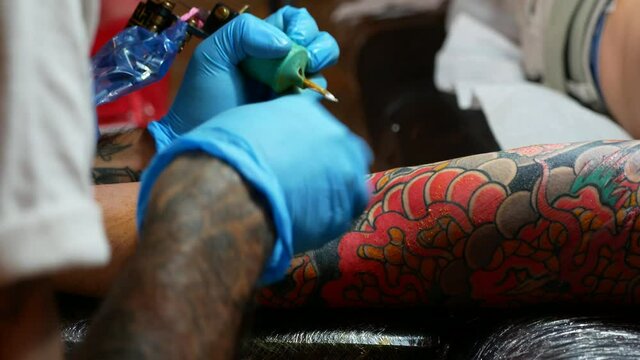 Close up of hands of an artist tattooing on a customer's arm.