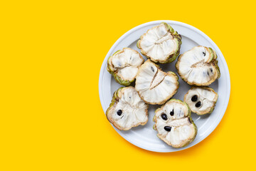 Custard apple in white plate on yellow background.
