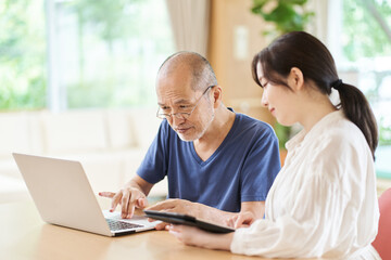 介護施設でパソコンの使い方を教えてもらう高齢者