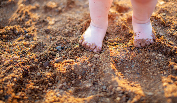 Children's bare feet in summer on a golden sandy beach close-up.