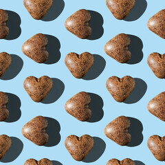 Photo in the form of a seamless pattern. Chocolate gingerbread in the shape of a heart of dark brown color with shadows on a colored light blue background.