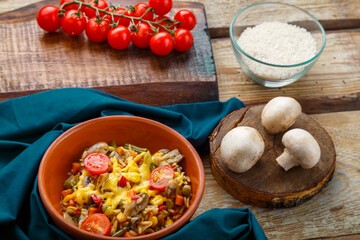 Risotto with mushrooms in a plate on a wooden background on a blue napkin and ingredients.