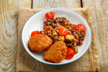 Cod cutlets with potatoes and vegetables on a plate on a napkin.