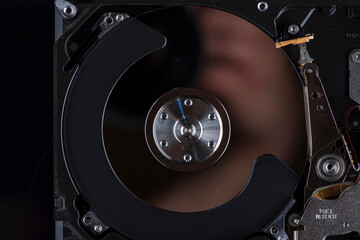 Fragment of a disassembled hard drive, against a dark background.
