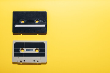 Fototapeta premium Two audio cassette tapes isolated on a yellow background. Copy space