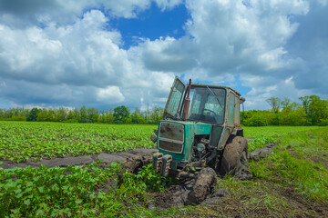 old farm tractor stuck in field dirt after rain