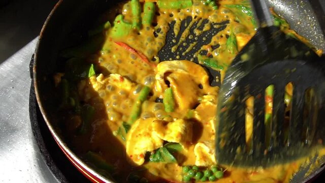 Chef cooking spicy Thai style food, pork with red curry
