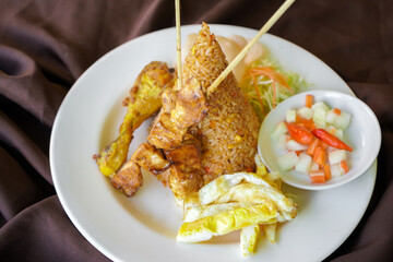 Chicken satay fried rice on white plate.
