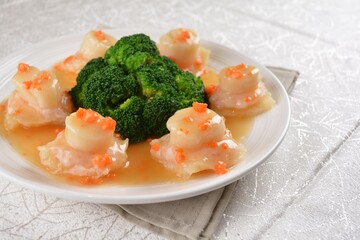 braised fresh scallop with fish maw, roe and broccoli in thick sauce in white background asian halal seafood menu