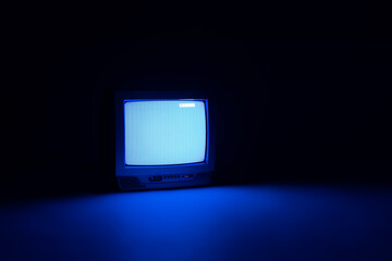 In the dark, there is a working blue screen old CRT TV that gives a light to the floor. Concept...