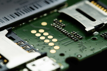 Smartphone from the inside angle view. Microcircuit, wires and details close-up on a green circuit board. Disassembled phone. Technology background. Selective focus