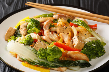 Tasty Stir fry mix of vegetables, chicken and tofu close-up in a plate on the table. Horizontal