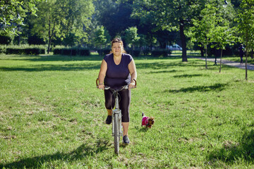 Body positive female rides bike in city garden at daytime. © grigvovan