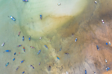 Fototapeta na wymiar .aerial top view fishing boats parking on the beach during low tide at Rawai beach Phuket Thailand..sea without water in low tide fishing boats stuck in the mud...sand beach background..