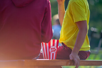 Children holding popcorn while sitting in summer cinema