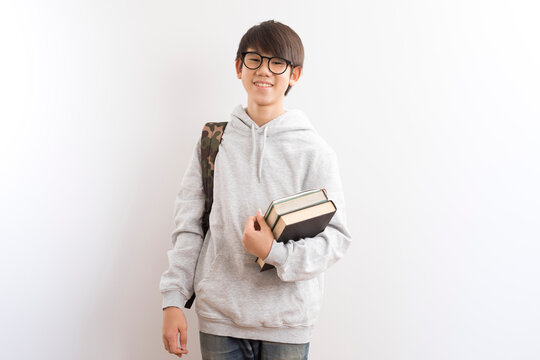 Asian teen student with school bag and books on white background.