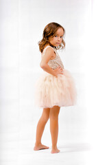 Portrait of happy pretty curly little girl standing and posing over white background