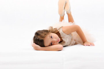 Portrait of happy pretty curly little girl laying on the floor and posing over white background , happy face girl concept