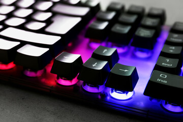 Modern keyboard with RGB lighting on grey table, closeup