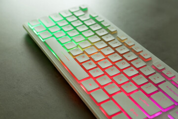 Modern keyboard with RGB lighting on grey table, closeup