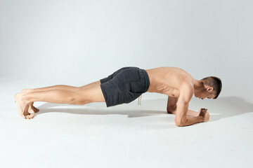 sports guy doing push-ups indoors on elbows in full growth