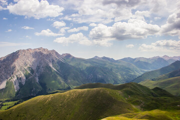 Beautiful Summer landscape: blue cloudy sky, green hills and distant mountains