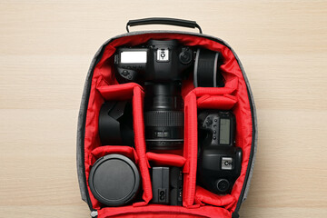 Professional photography equipment in backpack on wooden table, top view