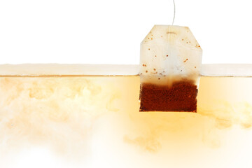Dipping of tea bag into hot water against white background