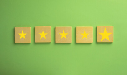 gold five star rating feedback icon on wooden cube over green pastel background use for Customer...