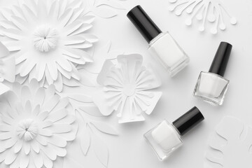 Bottles of white nail polish are aesthetically laid out on a white background with white paper...