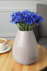 Bouquet of beautiful cornflowers in vase on wooden table at home