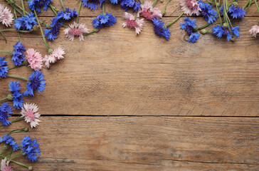 Obraz na płótnie Canvas Beautiful colorful cornflowers on wooden background, flat lay. Space for text