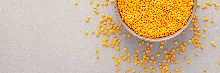Legumes in bowl and scattered in the background, lentils in a plate banner, top view, copy space