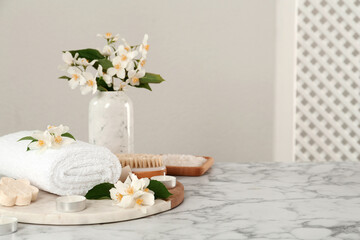 Obraz na płótnie Canvas Composition with beautiful jasmine flowers and folded towel on white marble table, space for text