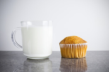 Cupcake and transparent cup of milk on gray granite table