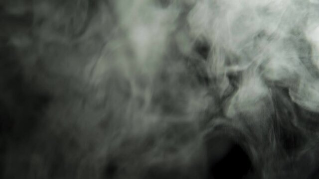 Clouds of dense smoke on a black background. The smoke moves and fills the space. Abstract background.