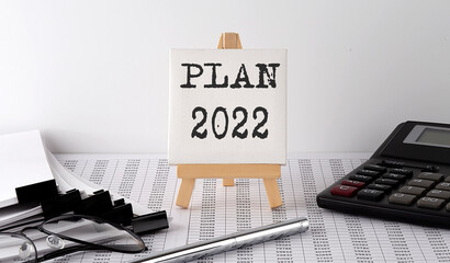 text PLAN 2022 on easel with office tools and paper.Top view. Business concept
