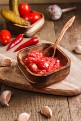 Appetizer, seasoning or sauce of tomatoes, horseradish and garlic in a wooden bowl. It is perfect for meat dishes. Close-up, no people, vertical orientation