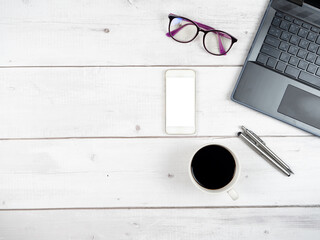 Top view workspace laptop glasses coffee cup and two silver pen with smartphone white screen copy space