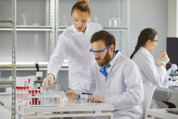 Group of serious scientists working in laboratory. Young pharma chemists or biotech science company...