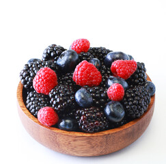 Fresh berries salad in a wooden plate on white background.