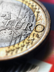 1 one euro coin lies on a bank plastic card. Focus on the name of the Eurozone currency. Vertical illustration with increased contrast and saturation about the economy of the European Union. Macro