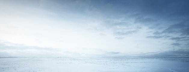 Panoramic view of the snow-covered field after a blizzard at sunset. Human tracks in a fresh snow....