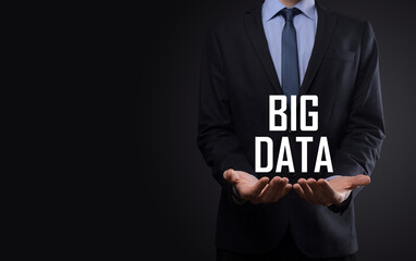 Businessman in a suit on a dark background holds the inscription BIG DATA. Storage Network Online Server Concept.Social network or business analytics representation